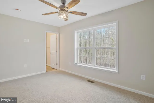 an empty room with chandelier fan and windows