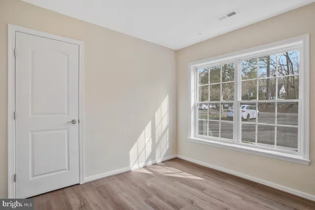 a view of an empty room with wooden floor and windows
