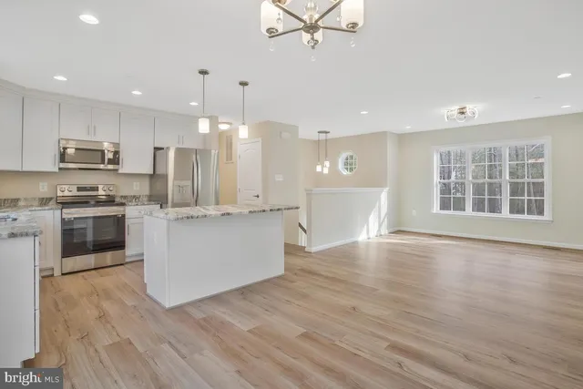 a large kitchen with stainless steel appliances granite countertop a stove a sink dishwasher and a oven with white cabinets