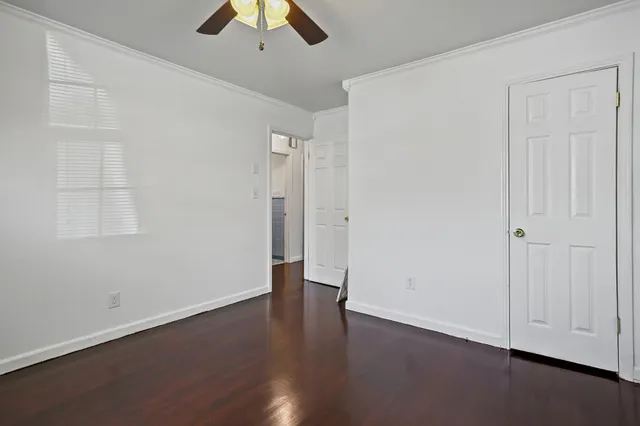 an empty room with wooden floor and ceiling fan