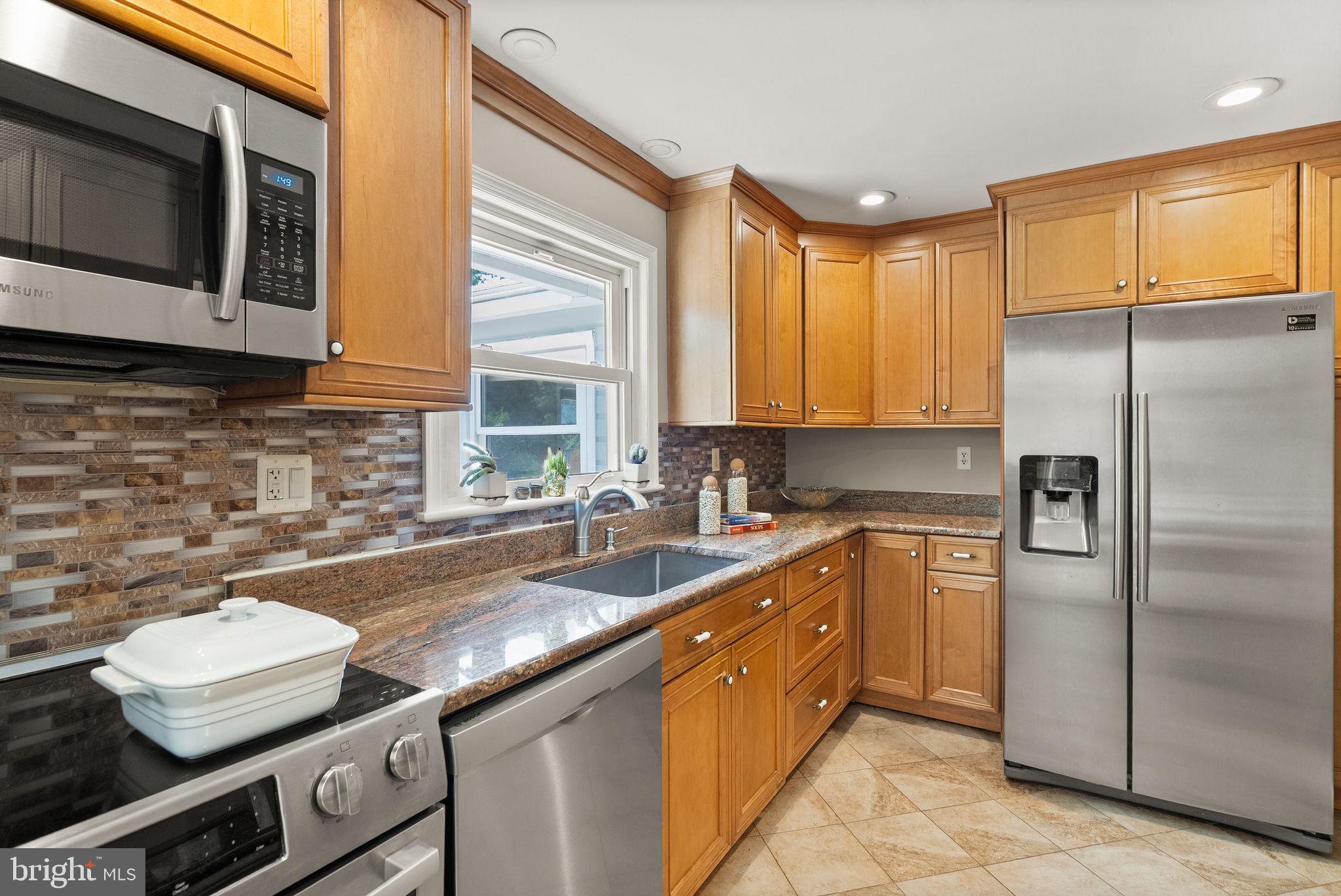815 Seneca Road Great Falls, VA 22066 - Photo 17 of 61 a kitchen with a sink a counter top space cabinets stainless steel appliances and a window