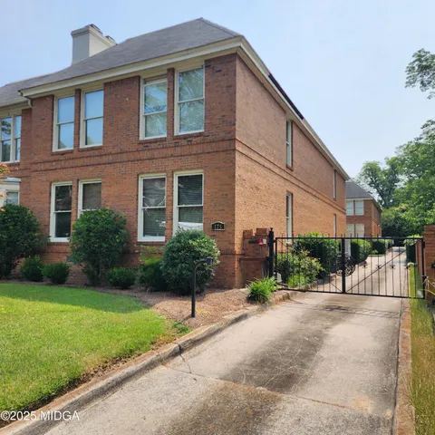 a view of a brick house with a yard and plants