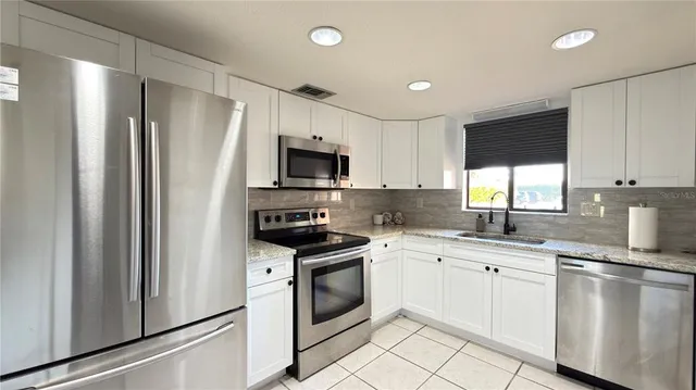 a kitchen with white cabinets stainless steel appliances and sink