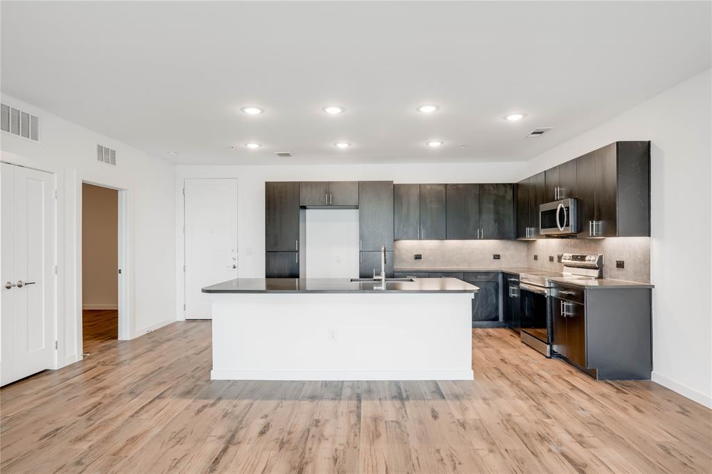 4801 Springdale Road, Unit 1307 Austin, TX 78723 - Photo 4 of 30 a large kitchen with stainless steel appliances a large counter top a stove and a wooden floors