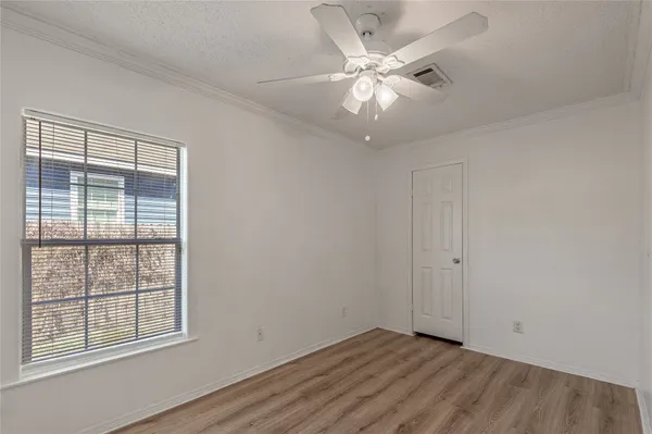 an empty room with wooden floor chandelier fan and windows