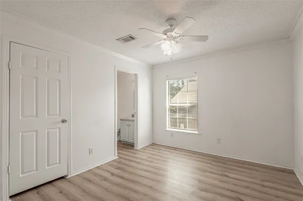 a view of an empty room with wooden floor and window