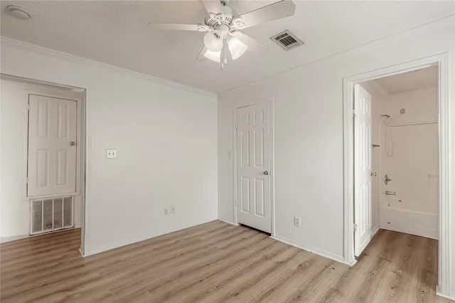 an empty room with wooden floor chandelier fan and windows