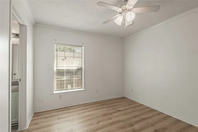an empty room with wooden floor and a ceiling fan
