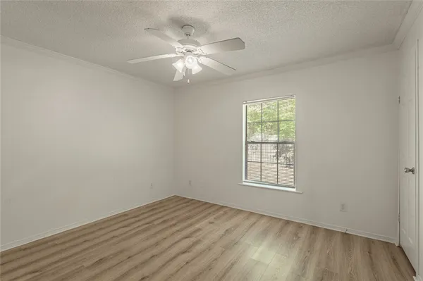 an empty room with wooden floor chandelier fan and windows