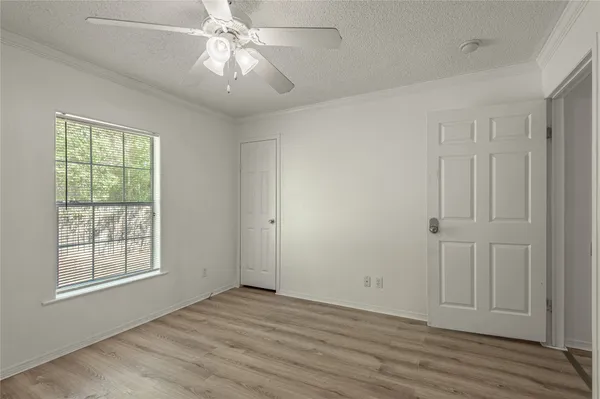 an empty room with wooden floor chandelier fan and windows