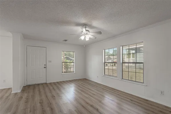 a view of an empty room with a window and wooden floor