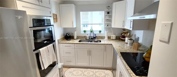 a kitchen with a sink a microwave a refrigerator and cabinets