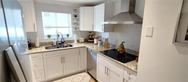 a kitchen with white cabinets a sink stove and refrigerator