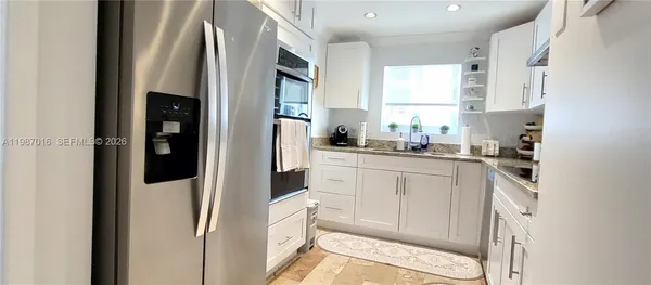 a kitchen with white cabinets and refrigerator