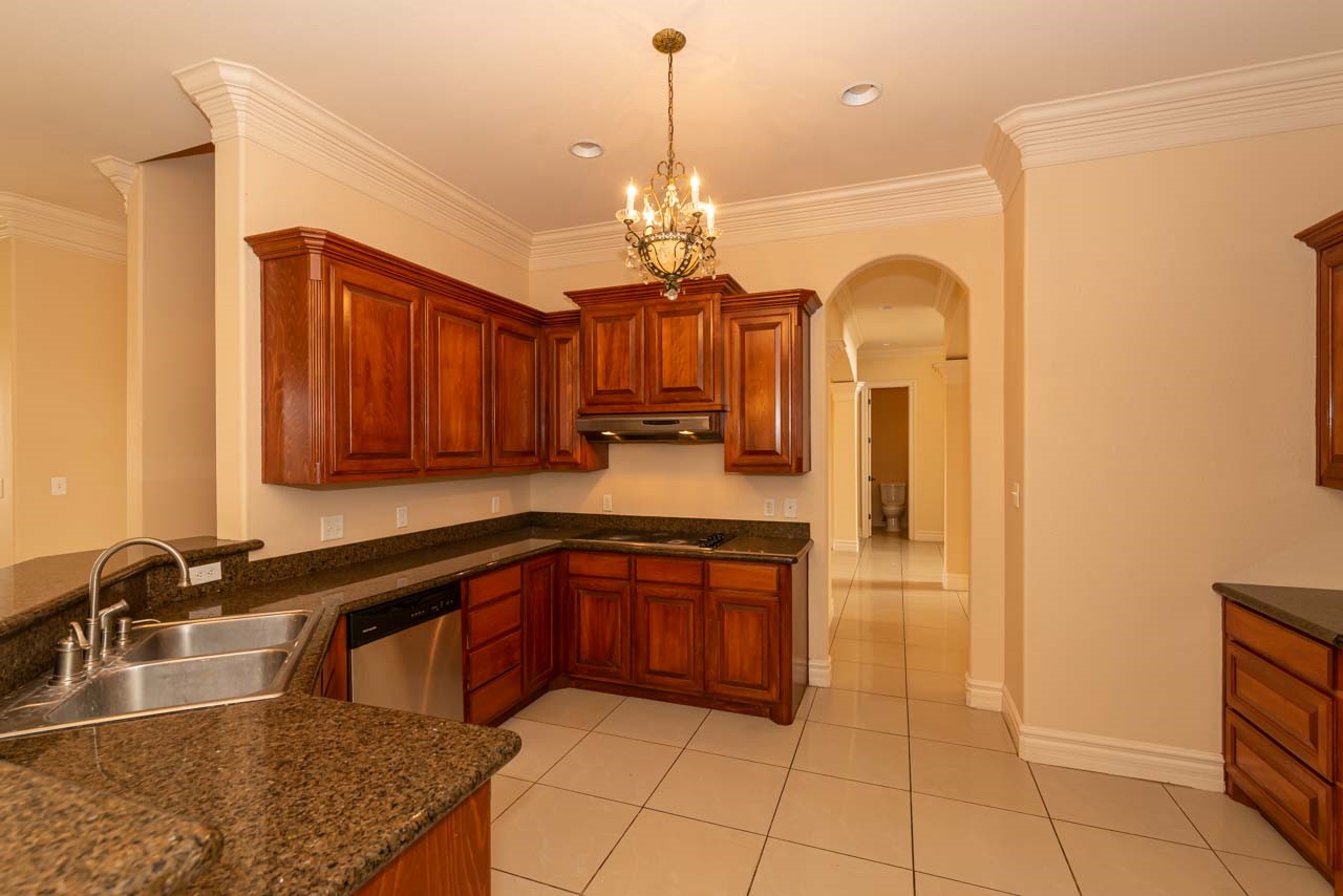 7 Stonebrook Court Beaumont, TX 77706 - Photo 17 of 35 a kitchen with stainless steel appliances granite countertop a sink dishwasher and a stove with wooden cabinets