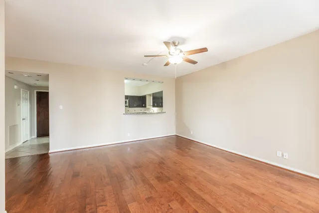 an empty room with wooden floor and ceiling fan