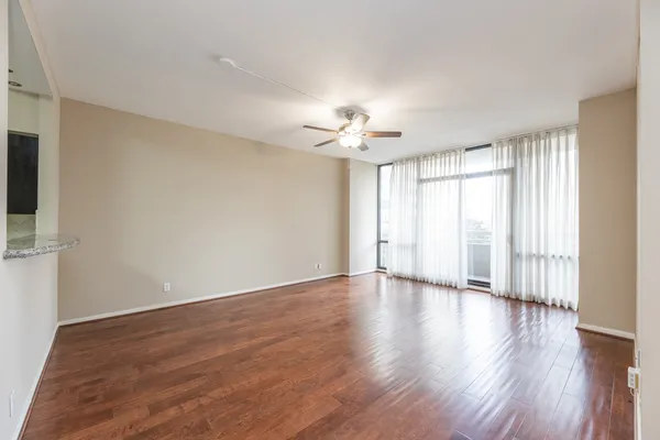 a view of an empty room with a window and wooden floor
