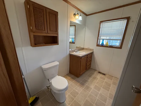a bathroom with a toilet a sink a mirror and vanity