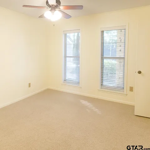 an empty room with a window and a ceiling fan