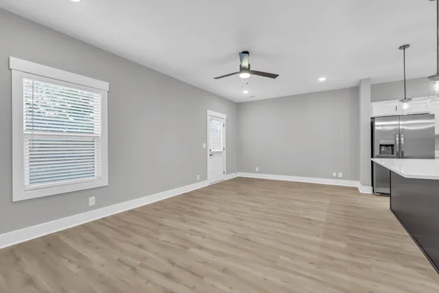 a large kitchen with stainless steel appliances a large counter top a stove a refrigerator and a view of living room with wooden floor