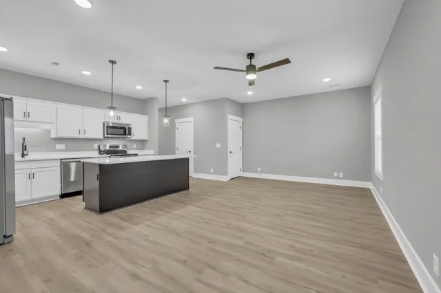 a kitchen with kitchen island a sink dishwasher a refrigerator and a oven with wooden floor