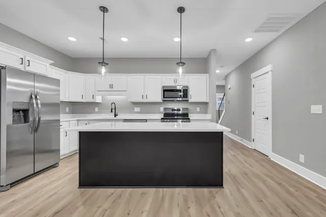 a kitchen with stainless steel appliances granite countertop a sink a stove top oven a refrigerator with white cabinets