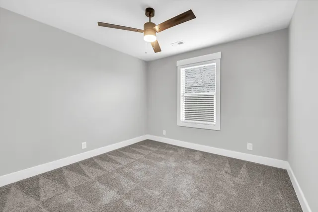 an empty room with a window and ceiling fan