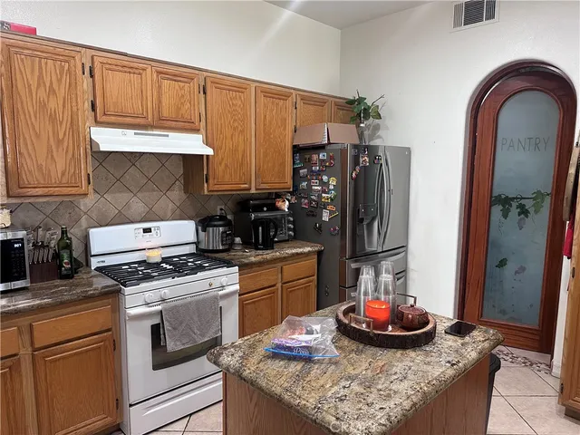 a kitchen with stainless steel appliances kitchen island granite countertop a sink stove and refrigerator