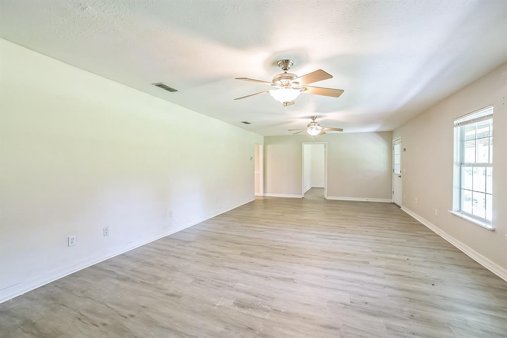 2861 Fm 727 Jefferson, TX 75657 - Photo 17 of 35 an empty room with wooden floor chandelier fan and windows