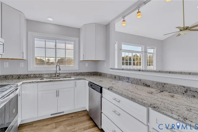 a kitchen with granite countertop a sink window and cabinets