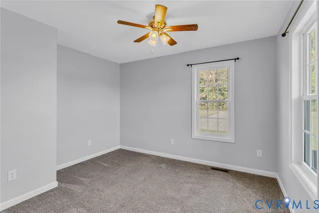 a view of an empty room with window and chandelier fan