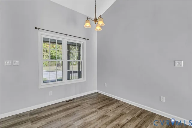 a view of an empty room with window and chandelier fan