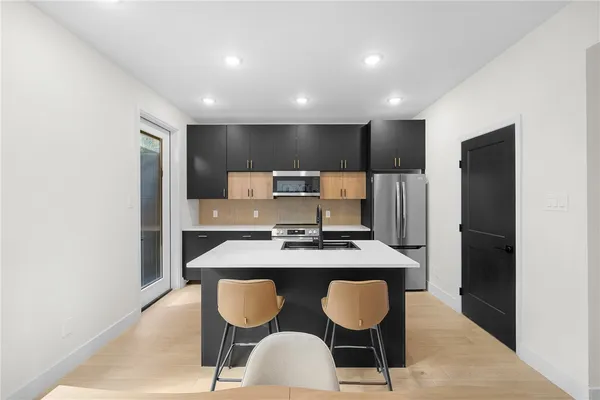 a kitchen with cabinets a refrigerator and chairs