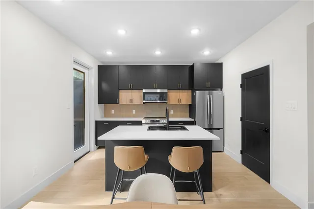 a kitchen with cabinets a refrigerator and chairs