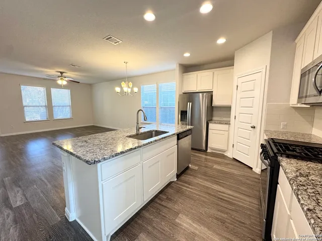 a large kitchen with stainless steel appliances granite countertop a lot of counter space and wooden floor