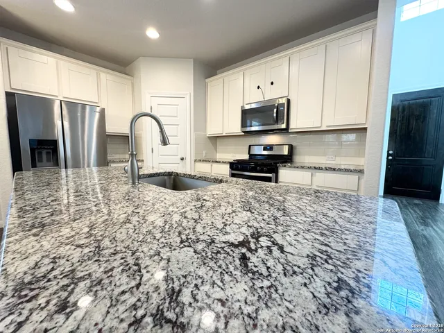 a kitchen with stainless steel appliances granite countertop a stove a refrigerator a sink a microwave and cabinets