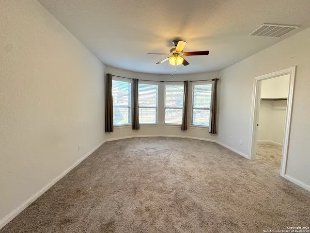an empty room with windows and chandelier fan