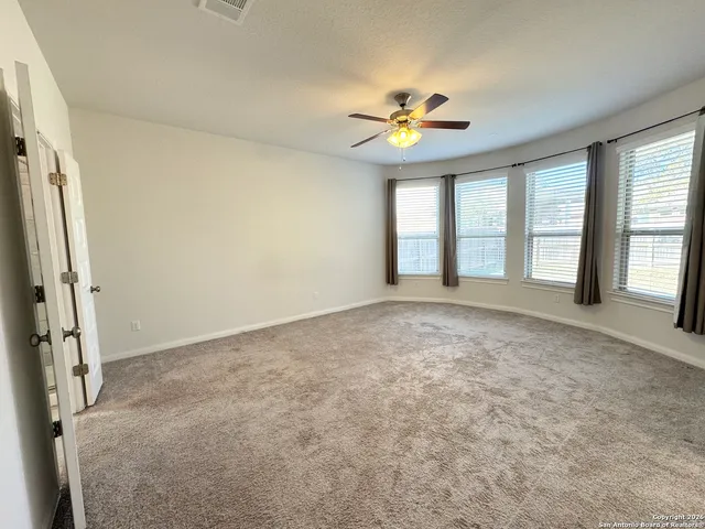 an empty room with windows and ceiling fan