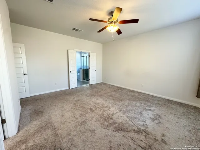 an empty room with a ceiling fan and a window
