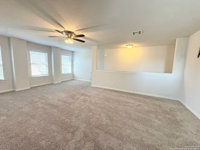 an empty room with windows and fan chandelier