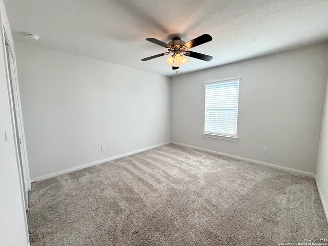 an empty room with a window and a ceiling fan