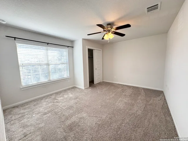 an empty room with windows and fan