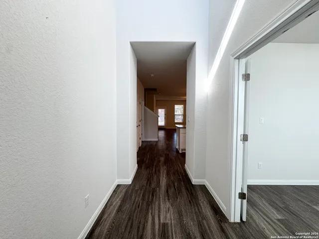 a view of a hallway with wooden floor and a living room