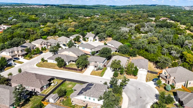 an aerial view of residential houses with outdoor space and trees