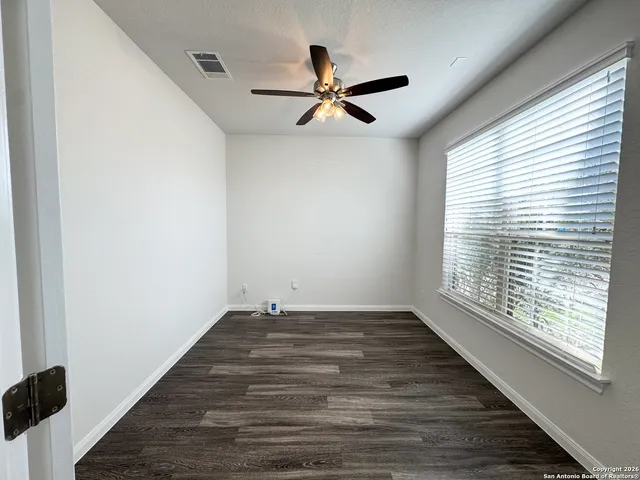 a view of empty room with wooden floor and fan