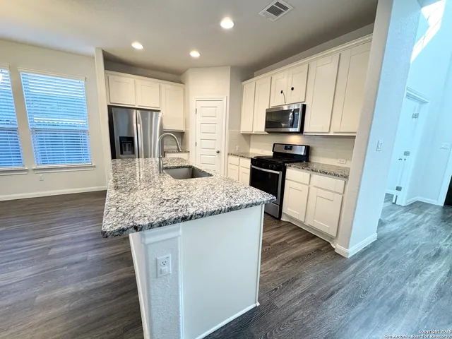 a kitchen with stainless steel appliances granite countertop a stove a sink and a refrigerator