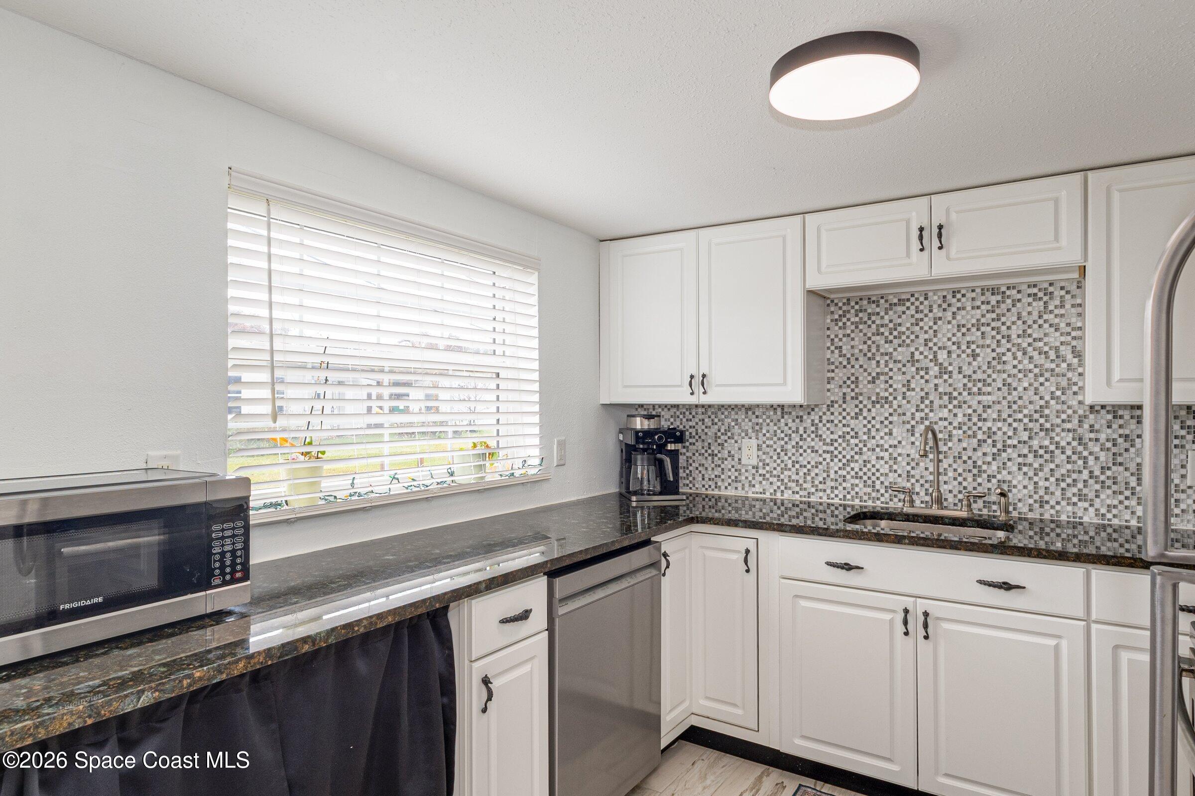131 Delmar Street Indialantic, FL 32903 - Photo 5 of 29 a kitchen with granite countertop white cabinets and a sink