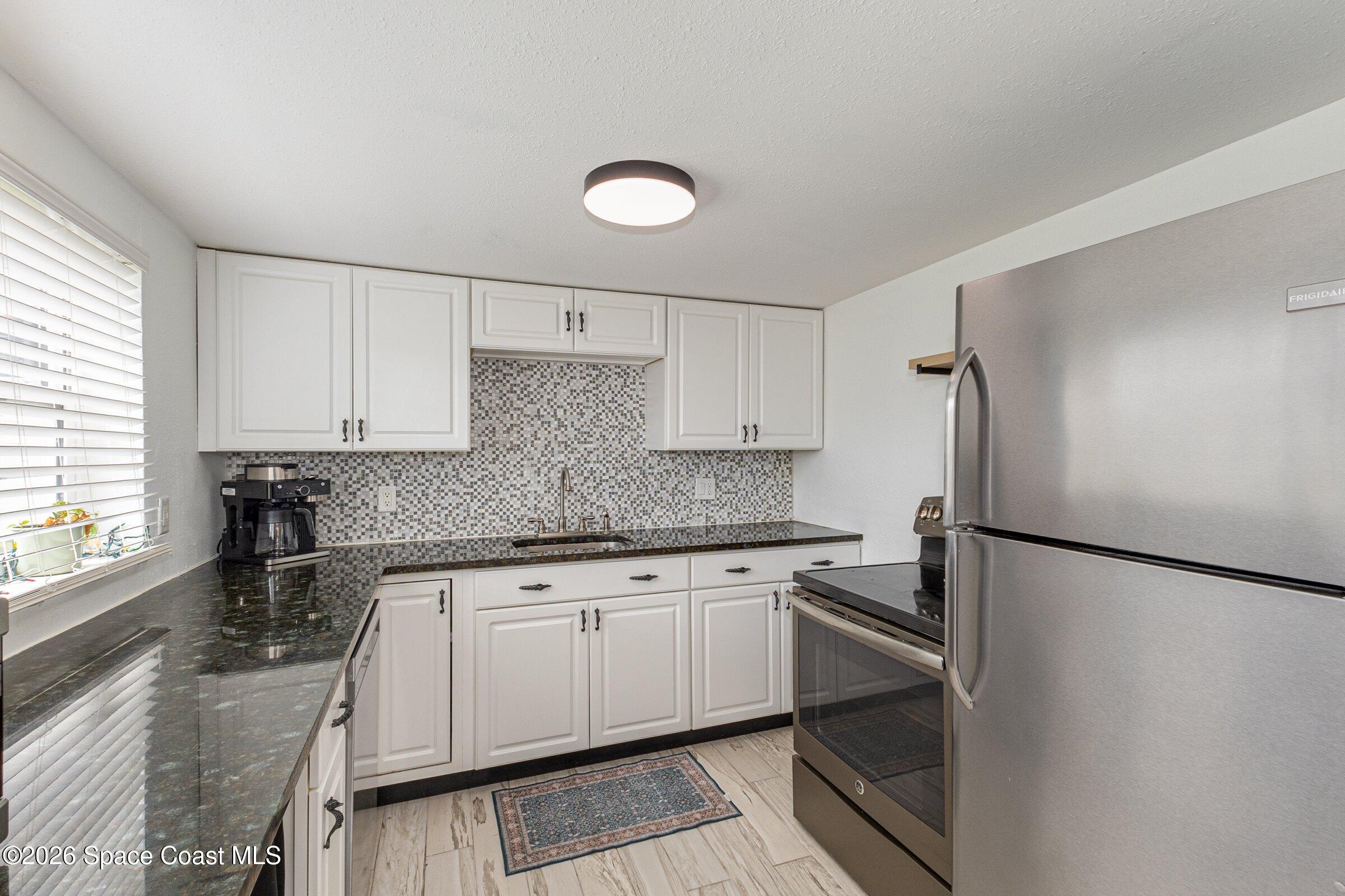 131 Delmar Street Indialantic, FL 32903 - Photo 6 of 29 a kitchen with a sink a refrigerator and cabinets