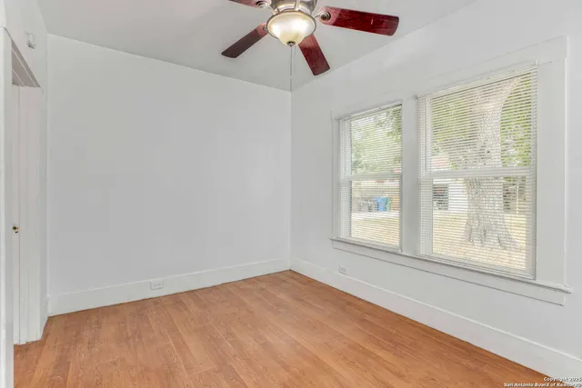 a view of an empty room with chandelier fan and fire place