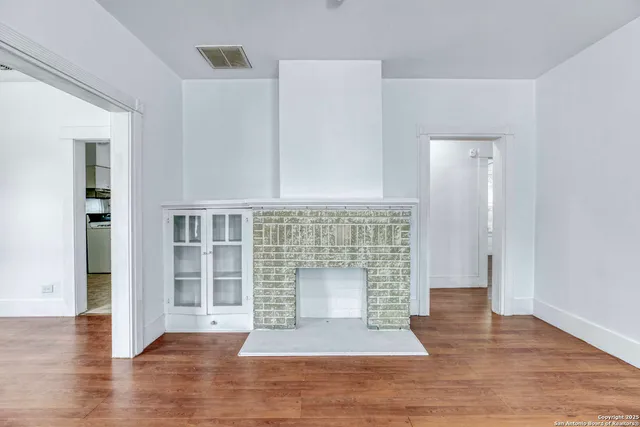 an empty room with wooden floor and fireplace
